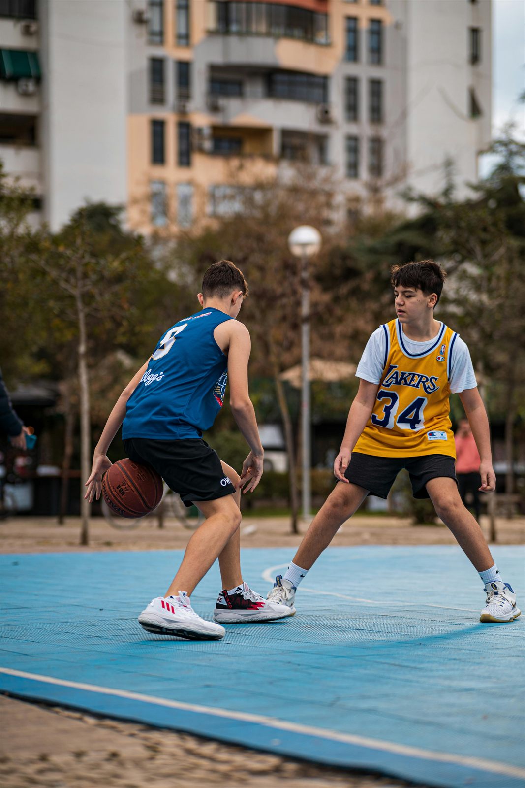 Unga spelar basket på en öppen utomhusplan nära bostäder.